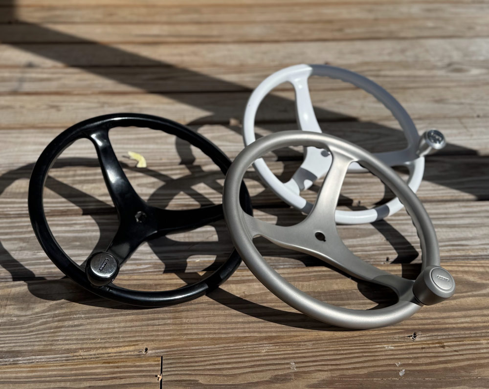 Three marine steering wheels on a weathered wood deck