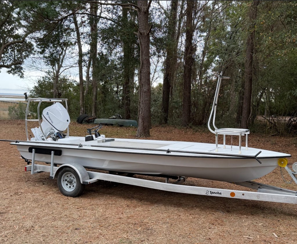 Lancha 18 skiff on a trailer beside the woods